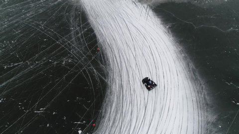Aerial top down view of go-kart also written as go-cart often referred to as simply a kart cornering over frozen lake track moving sideways left through corner winter sports activity 4k quality – Stockvideo
