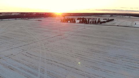 Aerial drone footage of a snow covered farmers field in Saskatchewan with the sunset. 4K 24FPS.