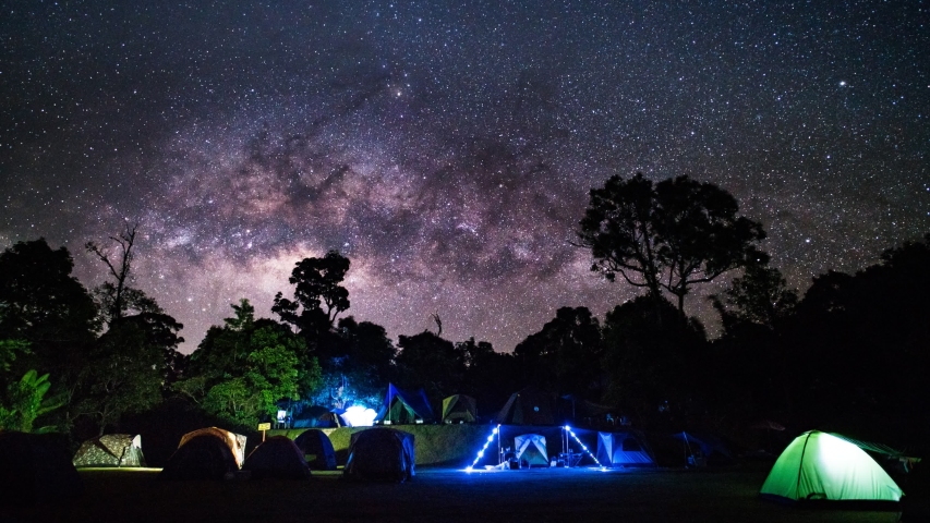 Time-lapse Camping group under the amazing milky way on sky. Travel outdoor activity concept. Tilt up..