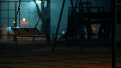 Swing in a playground foggy wet night