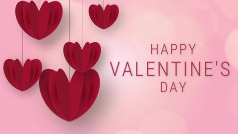 Happy valentine's day text on pink background with red paper hearts hanging. Beautiful and romantic valentine video.