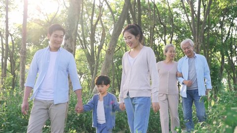 three generation asian family walking talking relaxing outdoors in park
