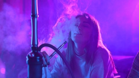 Woman with friends talking enjoying hookah at the bar feel happy young friendship communicate emotion shisha smoker male lounge handsome female vape beautiful attractive company relax slow motion
