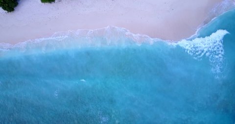 Paradise azure sea with white waves foaming over pink sand of exotic beach on a peaceful texture in Bermuda, copy space