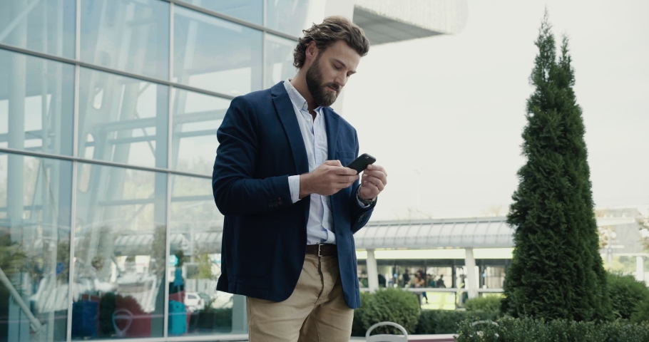 Attractive Star-up Businessman browsing his Phone near modern Office Build. Stylish Man texting Messages on his Smartphone. Man. Social Network. Working Process. Royalty-Free Stock Footage #1045774996