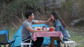 Men feed apple for young lovers at camping side in the nature park  young asian couple tourists picnic relaxation in the garden concept footage video 4K 