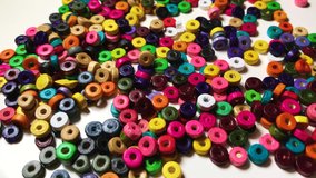 Group of colorful beads spilled on White Table composition wonderful interesting vibrant contrast colors 4K video Macro shot background image.