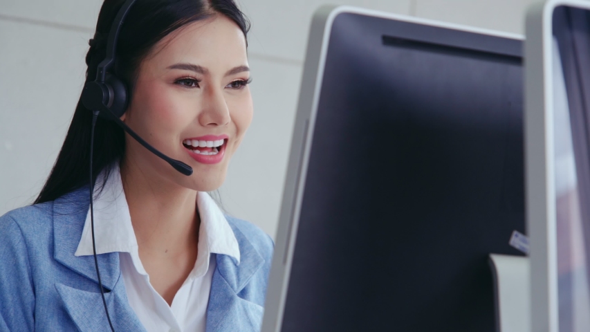 Customer support agent or call center with headset works on desktop computer while supporting the customer on phone call. Operator service business representative concept. Royalty-Free Stock Footage #1045803232