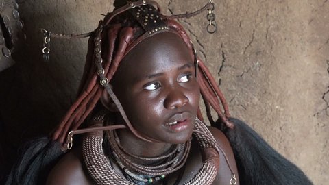 NAMIBIA, NOVEMBER 2019: Portrait of beautiful young tribal African Himba woman in national dress and a headdress