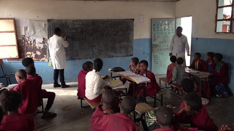 LALIBELA, ETHIOPIA – MARCH 2019: Students listen to math teacher writing on chalkboard inside classroom of primary school in Lalibela, education in developing country Ethiopia Africa