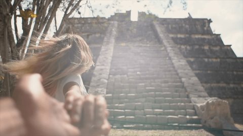 Follow me to concept, couple holding hands at Chichen Itza in Mexico. People travel concept, man's personal perspective of following girlfriend. woman leading man. Slow motion . leading the way