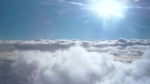Flying above layers of cloud, looking towards the sun and blue sky