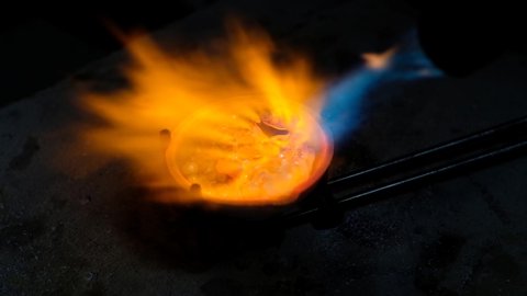 Goldsmith melting gold to liquid state in crucible with gasoline burner. Craft jewelery making with professional tools