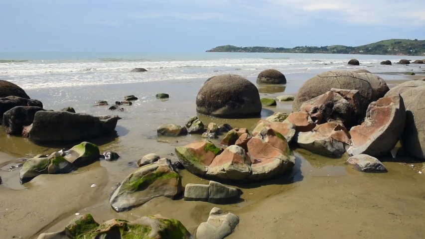 Moeraki boulders on Koekohe Beach on the Otago coast, New Zealand. One of the boulders in the foreground has disintegrated into pieces.