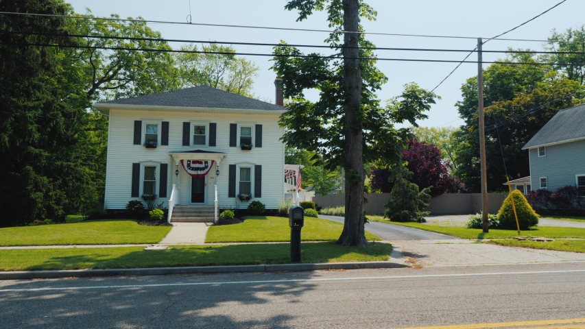 A typical American suburb street, wooden white houses and manicured lawns