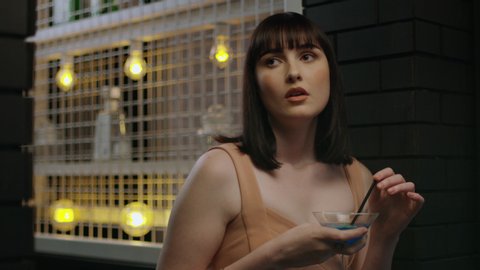 Good looking millennial woman looks board at bar waiting for friend in Australia. Medium shot pans up with 4K RED camera.