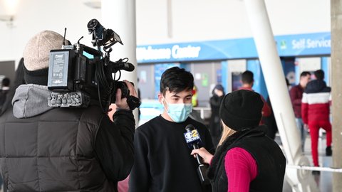 New York, USA - February 3th 2020: Jfk airport, American TV is interviewing a Chinese boy with a sanitaty mask about the coronavirus
