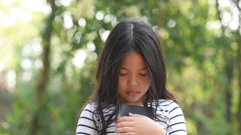 cute little asian girl in reading bible. hands holding on a holy bible. little child girl hands folded in prayer on a holy Bible for faith,spirituality and religion concept.