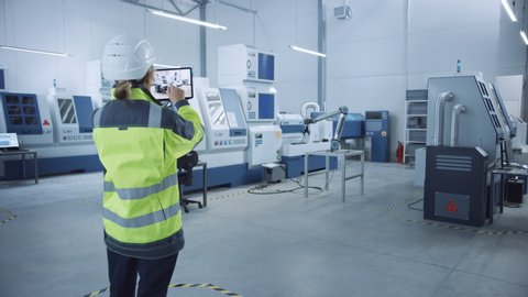 Industry 4.0 Modern Factory: Female Engineer Uses Digital Tablet Computer with Augmented Reality to Visualize Workshop Mapping, Floor Layout. Facility with High-Tech CNC Machinery and robot arm