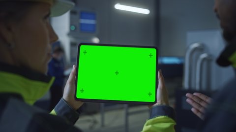 Industry 4.0 Factory: Chief Engineer and Project Supervisor in Safety Vests and Hard Hats, Talk, Use Digital Tablet Computer with Green Screen, Chroma Key. Workshop with Machinery. Zoom Out