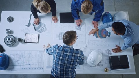 Team of Industrial Engineers Lean on Office Table, Analyze Machinery Blueprints, Architectural Problem Solving, Consult Project on Tablet Computer, Inspect Metal Component. Flat Lay Top Down View
