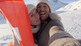Slow motion Selfie of young couple holding Swiss flag surrounded by mountain peaks in the Alps 