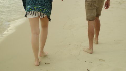 Young couple holding hands and walking along the beach near the water in Australia with soft day lighting. Medium shot on 4k RED camera