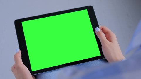 Green screen, mock up, entertainment, copyspace, freelance, template, leisure time, technology concept. Woman sitting on floor and looking at black tablet computer device with blank green display