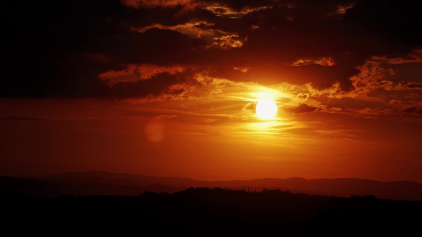 Beautiful red sunset in the evening cloudy sky over the Tuscan hills. Natural background. Video 4k