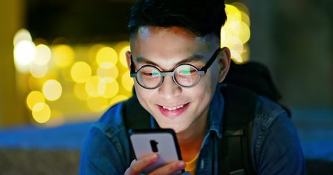asian young man use smart phone outdoor in the city at night