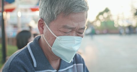 asian old man wear protective n95 mask because of transmissible infectious diseases or air pollution outdoor in the crowd