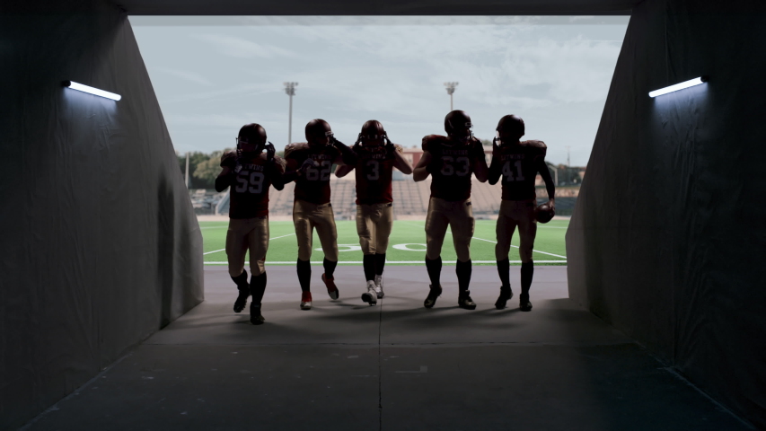 American football players walking through the stadium tunnel after team practice. 4K UHD,  Royalty-Free Stock Footage #1045952413