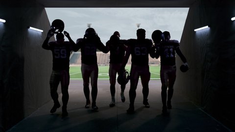 American football players walking through the stadium tunnel after team practice. 4K UHD, 