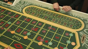 Casino: Croupier dealer woman hands on a game table of roulette. Player hands and chips bets. Close-up
