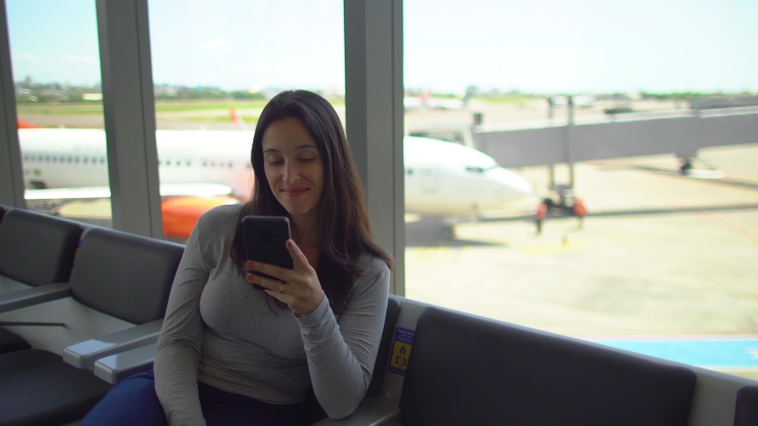 Relaxed woman waiting for flight at lounge area of airport. Lady sitting with phone mobile

