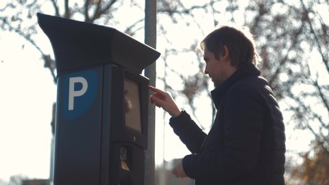 man inserting a parking lot ticket at an automated pay machine pay with card. Cash Automated machines parking lot in city attendants.