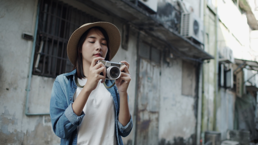 Beautiful Young Asian woman tourist taking photo with film camera street of old city  area of Bangkok Thailand. Solo trip concept in the vacation