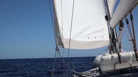 Mainsail and staysail at the close range. Sailing on yacht. Slow motion, swinging on waves. Summer voyage in the Atlantic ocean. Luxury vacation on sailboat 