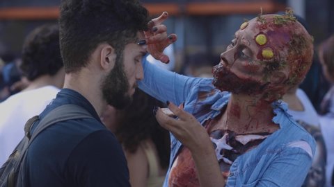 Rio de Janeiro , Rio de Janeiro / Brazil - 11 01 2019: Close-up of a make-up artist in style applying prosthetics before Halloween walk of zombies on the Day of the Dead in Copacabana