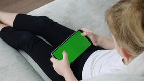 Smartphone with a green screen in hand child. Smartphone with a hromakey in the hands of a child.

