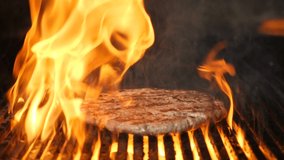 Cooking meat for burger on grill in slow motion. Flame rising up from grid. Beautiful slow motion food video. Hamburger being cooked in restaurant kitchen. Full hd
