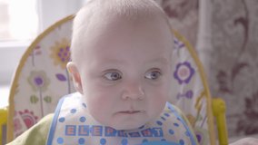 Mother gives to her cute little baby boy some pomegranate berries, son eating them and then grimacing spits out it close up view slow mo video in 4K