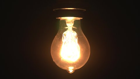 Tungsten light bulb lamp cozy turn on slowly and off over black background, close up shot of old retro vintage light bulb brighten light. Comfort cozy concept. 4k.