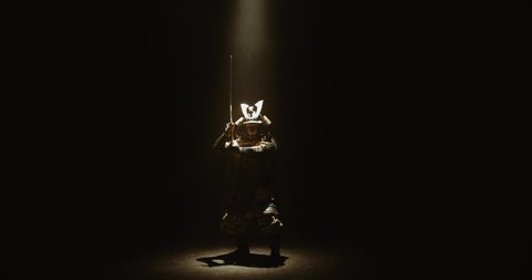 Asian man in traditional samurai costume stepping into the light with his sword prepared in hands, isolated on black background - culture, tradition concept 4k footage
