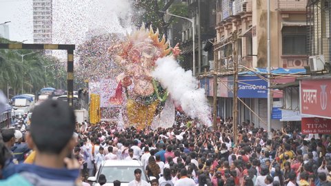 Paper Confetti sprayed on Ganapathi Idol during an immersion event. A huge crowd of people or devotees are standing on the streets to lead the procession, Ganesh Chaturthi, Mumbai, India (August 2019)