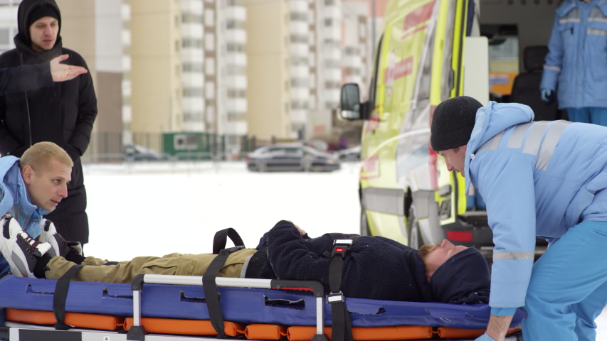 Sequence of shots of team of paramedics transporting unconscious patient on stretcher and loading him into ambulance Royalty-Free Stock Footage #1046005270