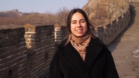 Happy woman walk at Great Wall of China, come down from watch tower at Badaling section at sunset in winter