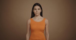 Displeased brunette woman swears and getting angry isolated on brown background