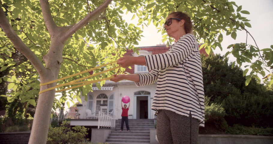 WS Senior Woman Exercising on Garden Lawn, as Senior Men Leads Her to Home. Shot in R3D (6K RED RAW)