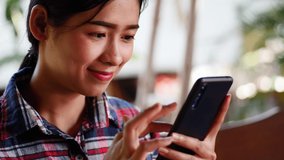 Young asian woman using mobile phone to chat with friend, smile happy feeling.